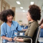 miami patient care technician program graduate working in hospital - checks patient in wheelchair