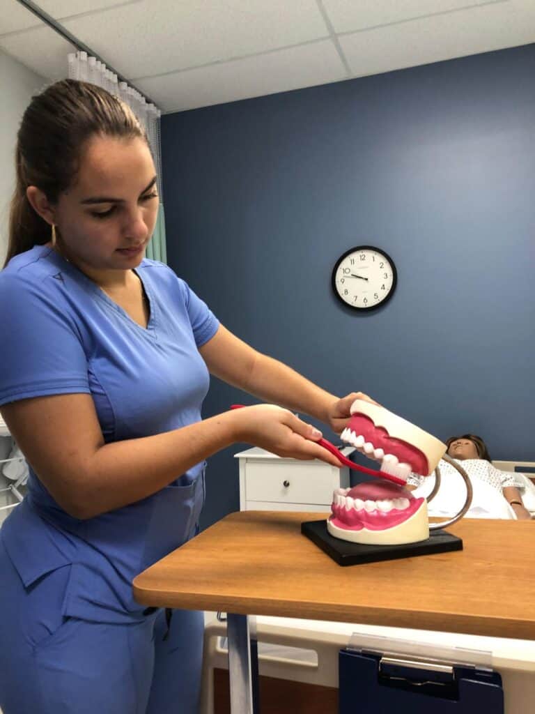 A miramar nursing assistant home health aide school student practicing dental hygiene on a simulated mouth