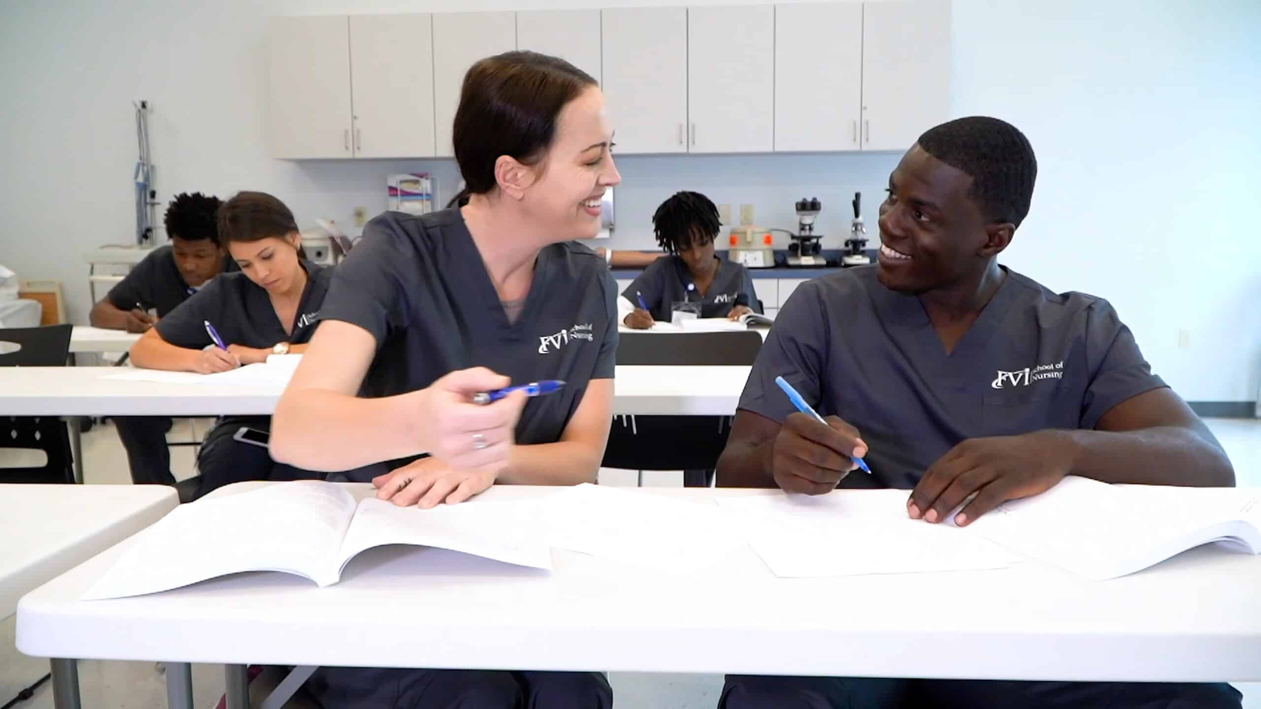 FVI south florida ASN nursing school students sitting in class smiling at each other studying from books