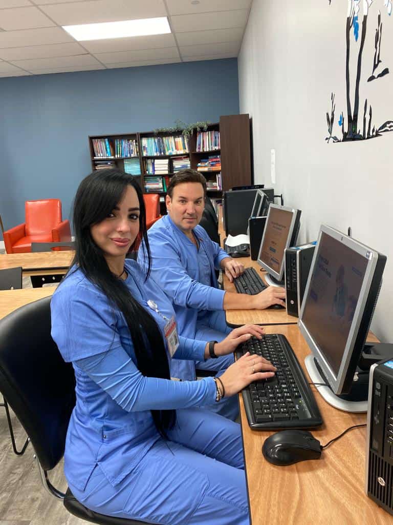 Two FVI Miramar allied health school students in scrubs working at the lab